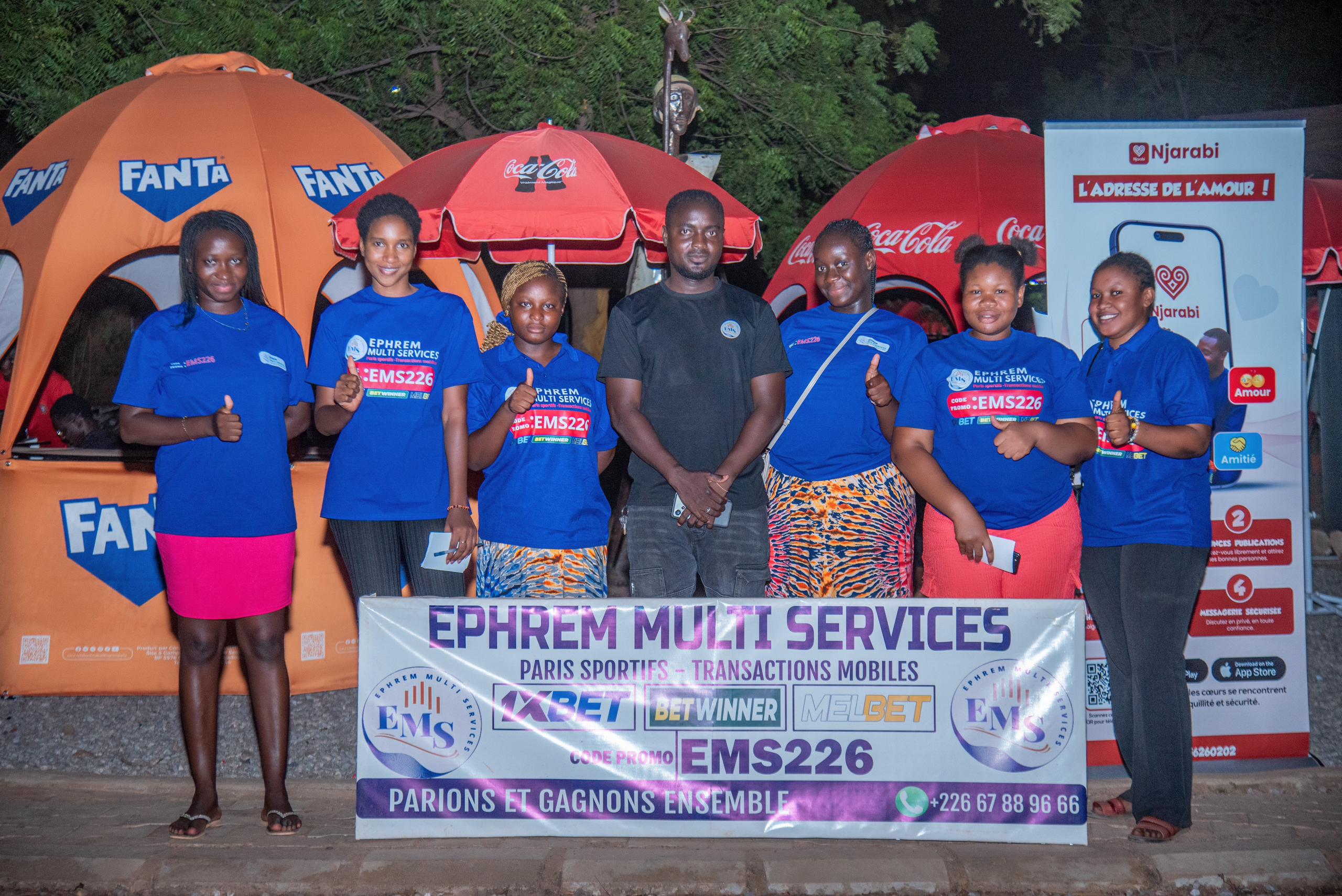 Équipe Ephrem Multi Services devant la banderole EMS lors d'un festival